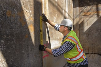 Caucasian construction worker holding level against wall