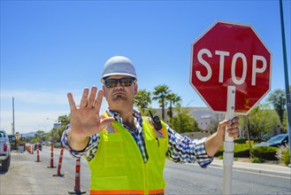 Caucasian flagger gesturing stop with stop sign