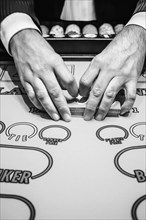 Dealer shuffling playing cards at baccarat table
