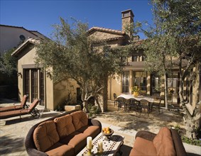 Rear exterior of Tuscan home with sitting and dining areas