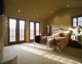 Master bedroom with vaulted ceiling and window light spilling through double french doors