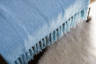 Blue throw blanket with tassels hanging over chair