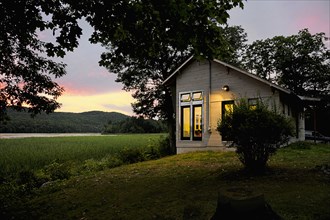 Exterior of a cabin with clapboard siding by lake at dusk