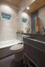 Contemporary bathroom with cropped bath and washbasin at mirror