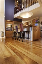Chairs by kitchen island and hardwood flooring in house