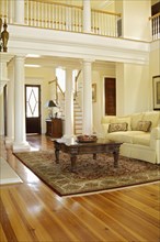 Traditional living room with support columns and loft with railing