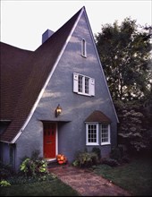 Exterior gray cottage style house with pointed roof and red door at Chico