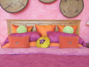 Pink and orange throw pillows on bed