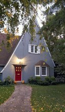 Exterior gray cottage style house with pointed roof and red door at Chico