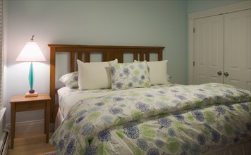 Bed in bedroom with blue and green comforter