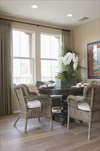 Wicker chairs around dining table by window at home