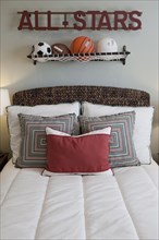 Balls over arranged pillows on tidy bed in the bedroom at home