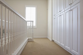White railings and cabinets along hallway at home