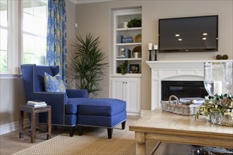 Flat screen TV above fireplace with blue chaise lounge in the living room at home