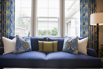 Close-up of cushions on blue couch against window in the living room at home