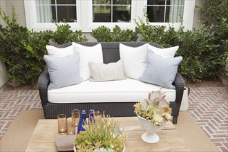 Wicker couch with cushions on brick flooring at a patio