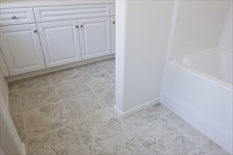 High angle view of cropped white cabinets and tiled floor at home