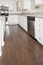 Kitchen having white cabinets and wooden floor at home