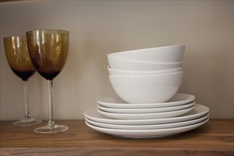 Bowls with plates and glasses on shelves in cabinet