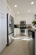 Kitchen having white cabinets and stainless steel refrigerator at home