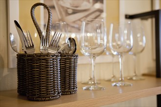 Close-up of cutlery and wine glasses on shelf in cabinet