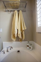 Bathroom with hanging towels over cropped bathtub
