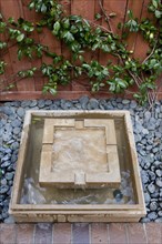 Square shaped fountain and pebbles outside house