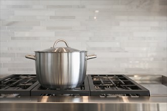 Sauce pan on burner with backsplash in kitchen