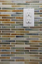 Close-up of tile backsplash with electrical socket