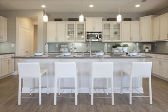 White bar stools at breakfast bar in domestic kitchen
