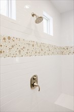Shower with white tiled wall in domestic bathroom