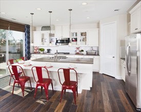 Kitchen island with red bar stools in house