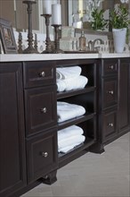 View of clean towels in brown cabinets with candle holders on counter at home