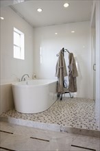 View of a bath with bathrobes on stand in the bathroom