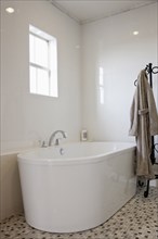 View of a bath with bathrobe on stand in the bathroom