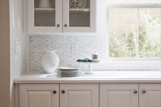 White cabinets and glass cabinet with crockery on counter top at home