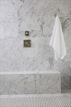 White towel and tap on marble wall in the bathroom at home