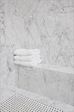 Folded white towels on marble seat in the bathroom at home
