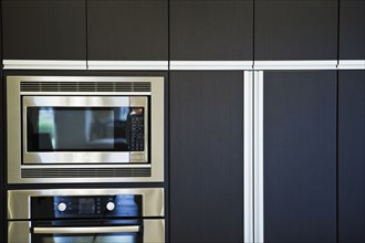 Microwave and oven surrounded by contemporary wooden cabinets