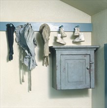 Bonnets and baby shoes hanging above blue cabinet