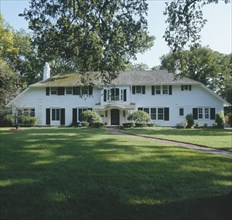 Facade of traditional white frame house with large lawn