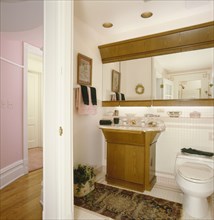 Commode with pedestal sink at mirror in the bathroom