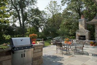 Outdoor seating furniture with stove and fireplace at patio of home.