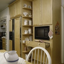View of microwave with wooden cabinets and refrigerator