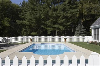 View taken from picket fence across length of pool. Area surrounded by white picket fence