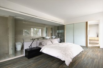 Modern bedroom with glass wall through to bathroom