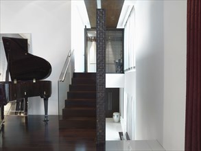 Baby grand piano next to staircase in modern home