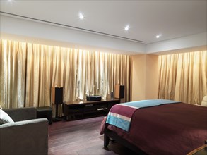 Bedroom with gold curtains and hardwood floor