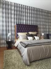 Elegant modern bedroom with purple velvet headboard