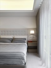 Bed with gray striped sheets in modern bedroom